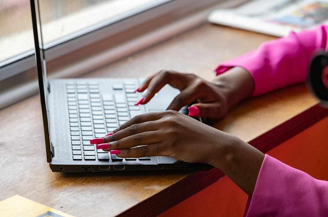 Hands typing on a laptop keyboard at a desk